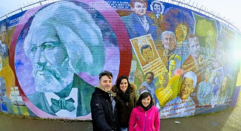 Tres viajeros ante uno de los murales políticos de Belfast