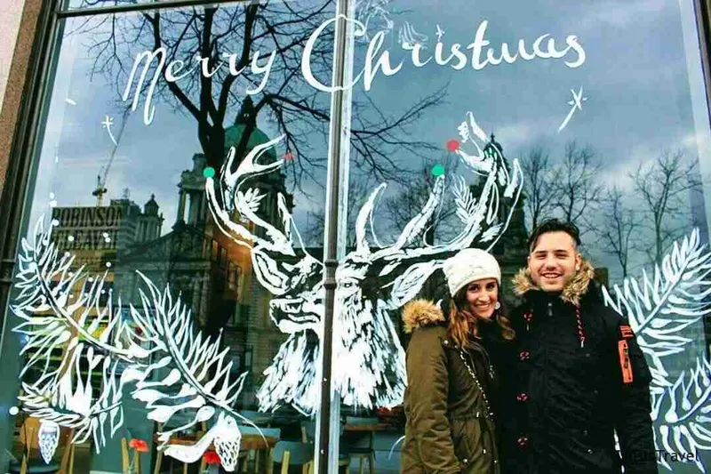 Pareja tras un escaparate decorado con renos y «Merry Christmas»