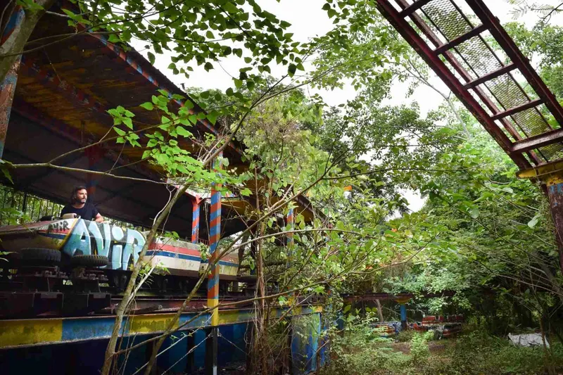 Restos de una atracción entre la maleza del parque