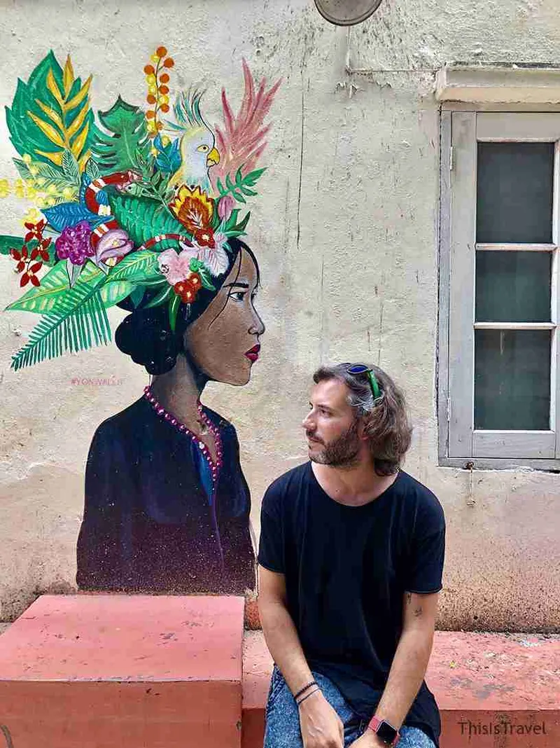 Mural de una mujer con tocado tropical, con una persona delante