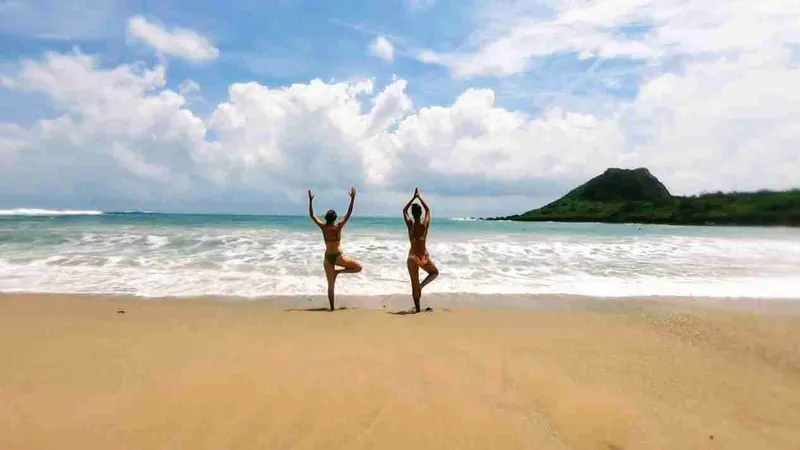 Dos personas haciendo la postura del árbol en la playa de Kenting