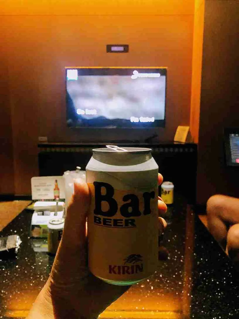 Lata de cerveza Kirin en la mano frente a la tele del hotel
